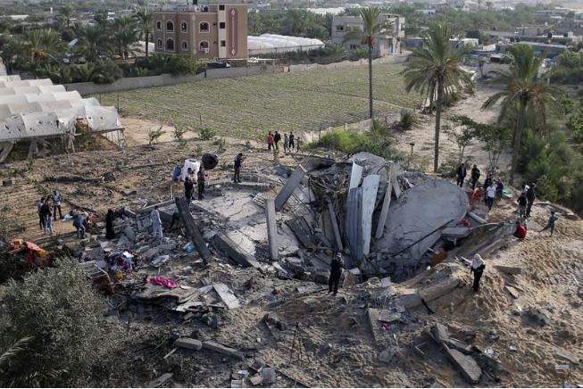 فلسطينيون يتجمعون حول أنقاض منزل دمرته غارة جوية إسرائيلية في جنوب قطاع غزة. تصوير: إبراهيم أبو مصطفى - رويترز.